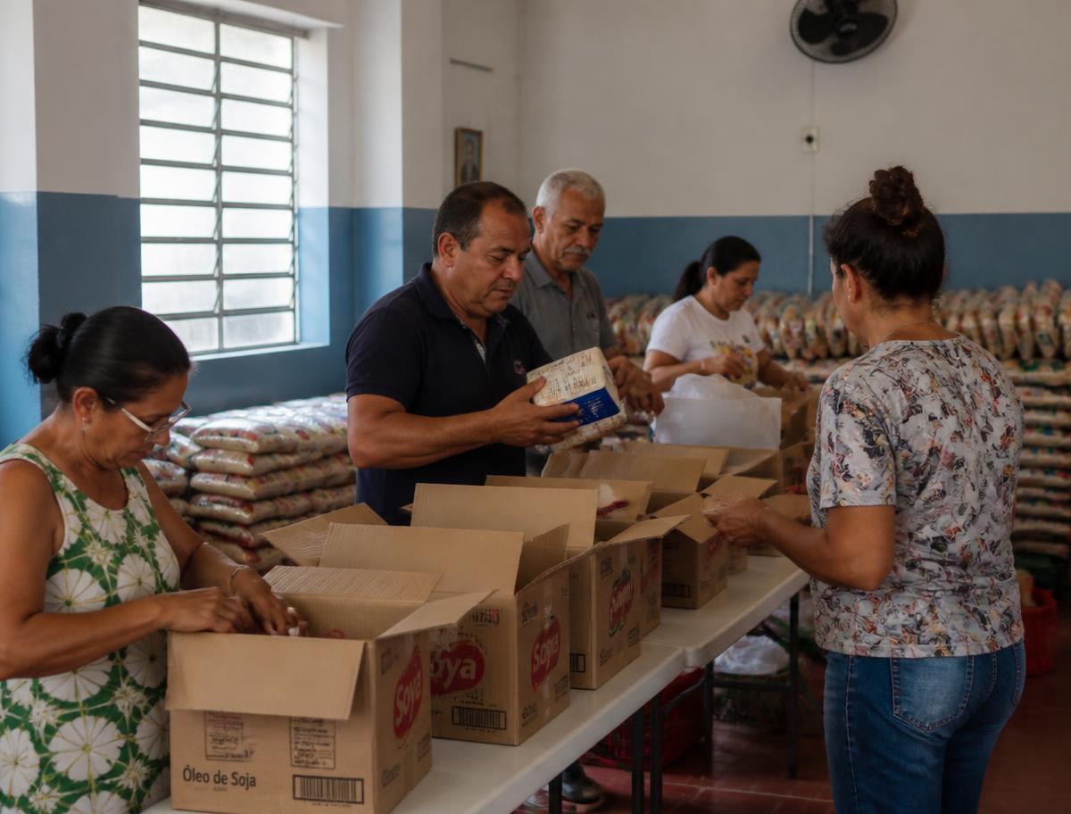 Voluntários montando cestas básicas em um salão comunitário